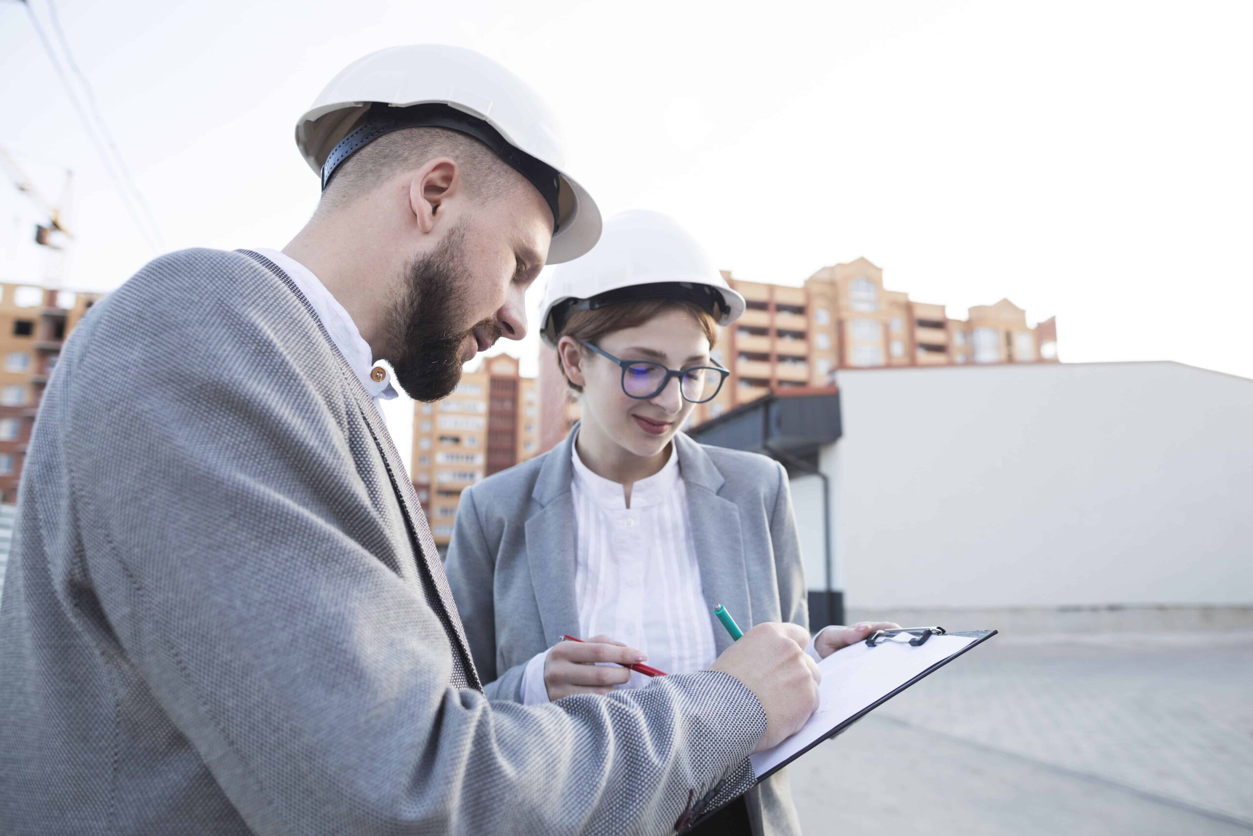 Engineers in safety helmets reviewing notes at construction site for utility mapping and private utility locating with verified field data.