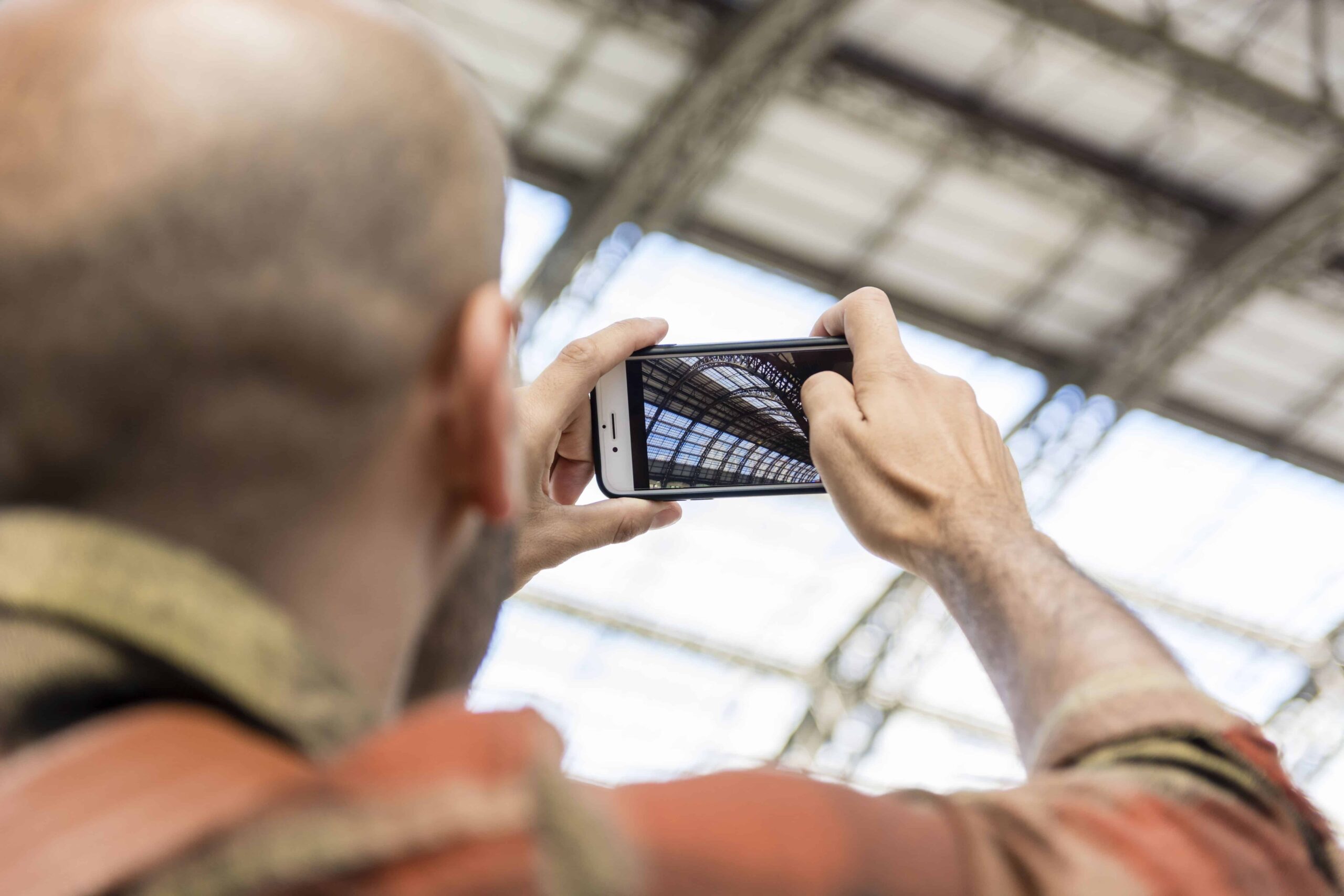 Construction worker in industrial warehouse documenting concrete scanning field process with smartphone, including site walk, grid scan, and utility marking for safe core drilling.