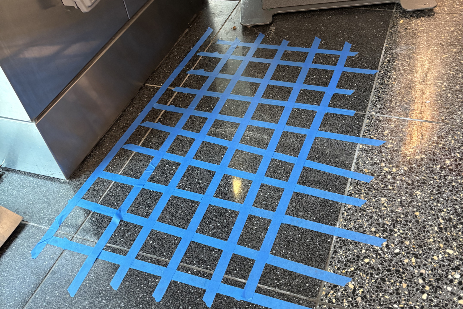 Utility locating and mapping at San Diego International Airport with blue tape grid on flooring for site improvement planning.