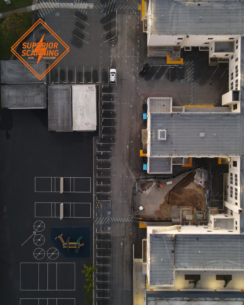 Aerial view of a Los Angeles campus with buildings, parking lots, access roads, and paved work areas for private utility locating.