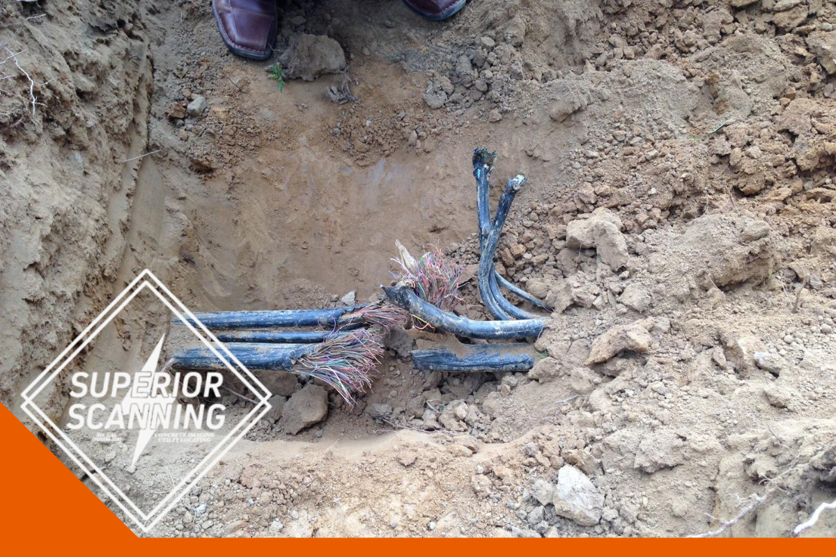 Damaged underground cables exposed in a trench, with frayed wires and black protective sheathing visible.