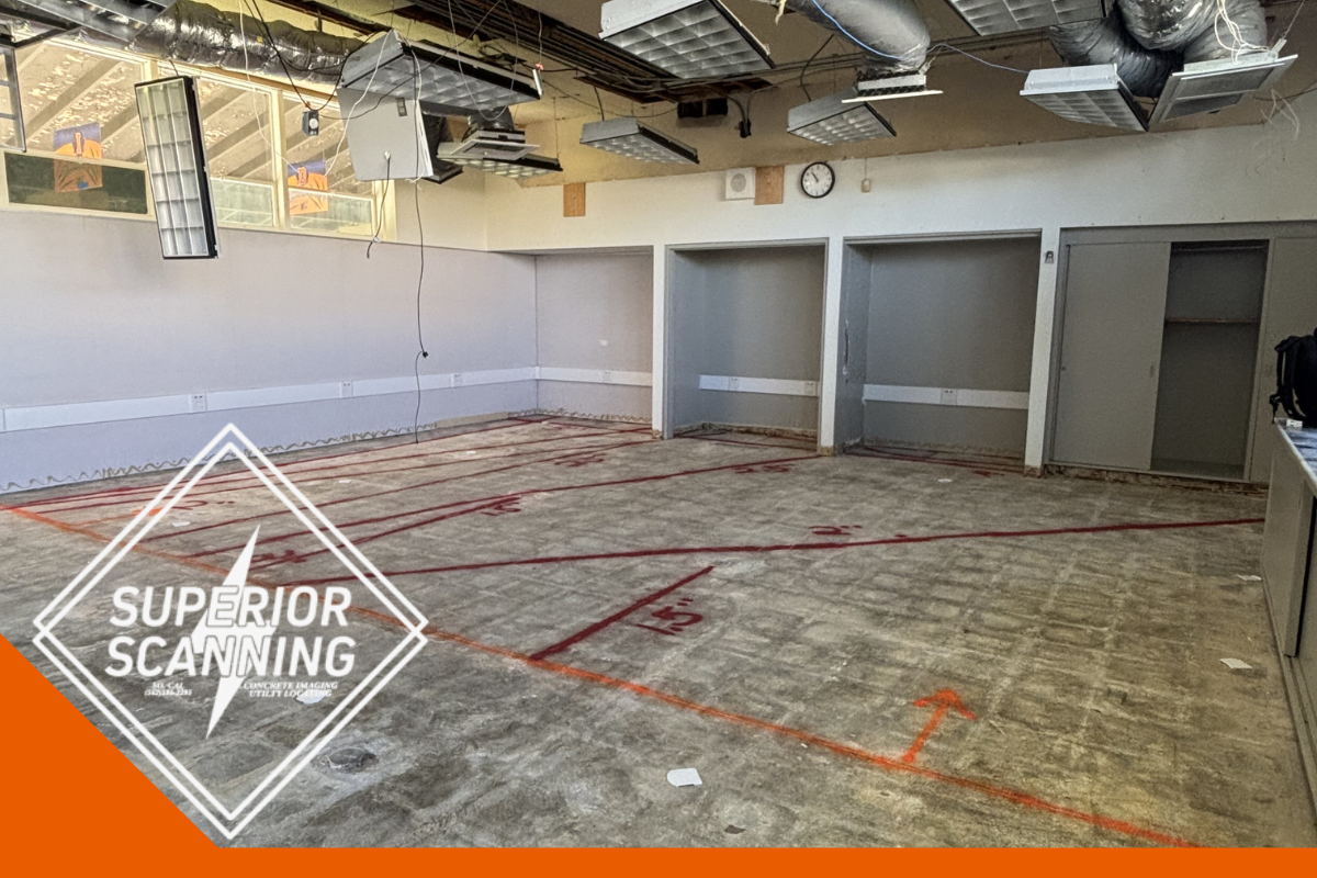 The floor of a room is marked with red lines and numbers, indicating a layout or measurement plan. The ceiling has exposed ductwork and light fixtures. There are doorways and blank walls visible.