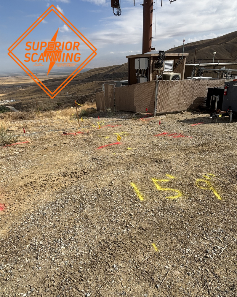 A construction site with markers and numbers spray-painted on the ground, with a tower and building in the background.