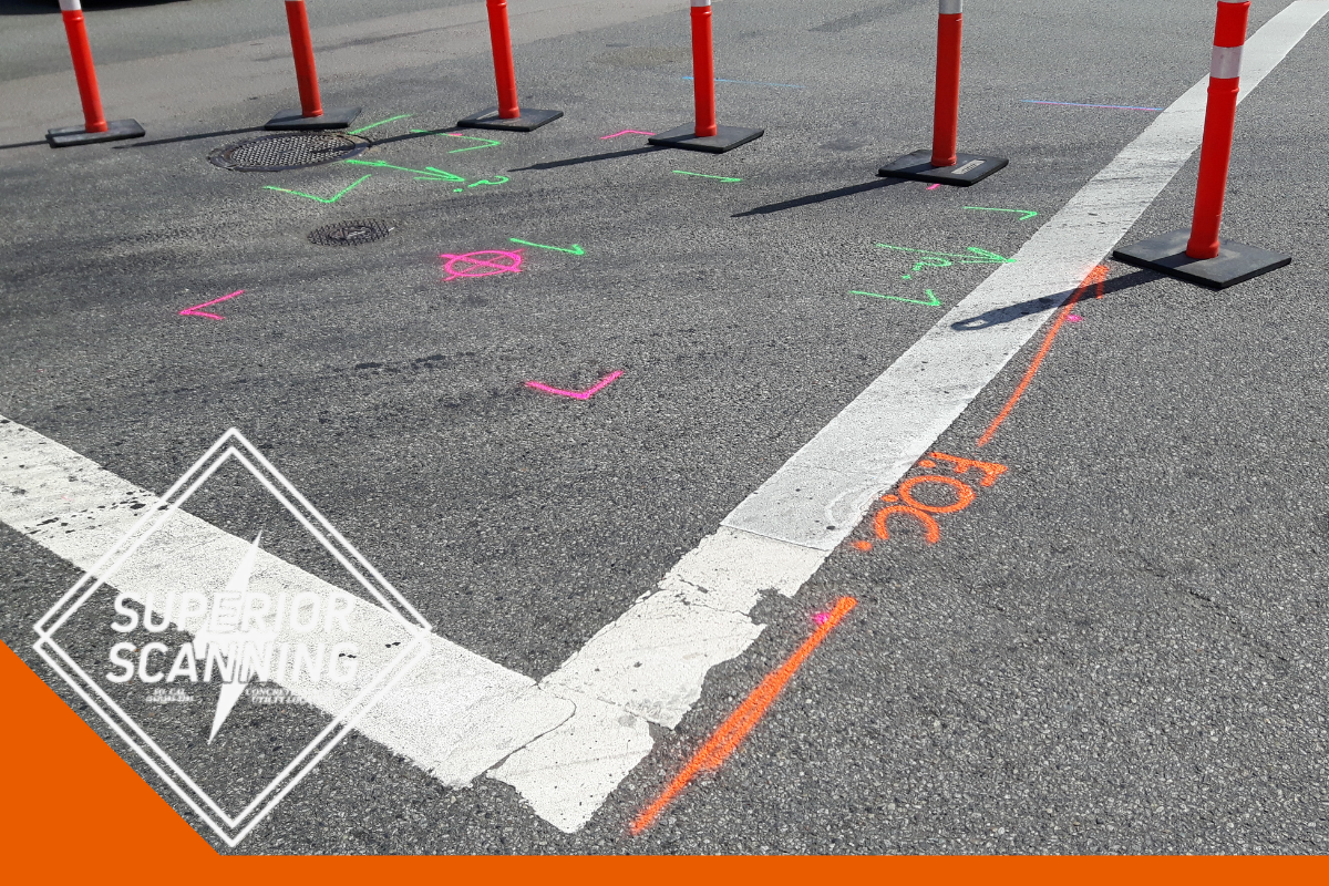 Orange spray paint marks, including the letters "FOC", are visible on asphalt next to a white line and orange traffic cones.