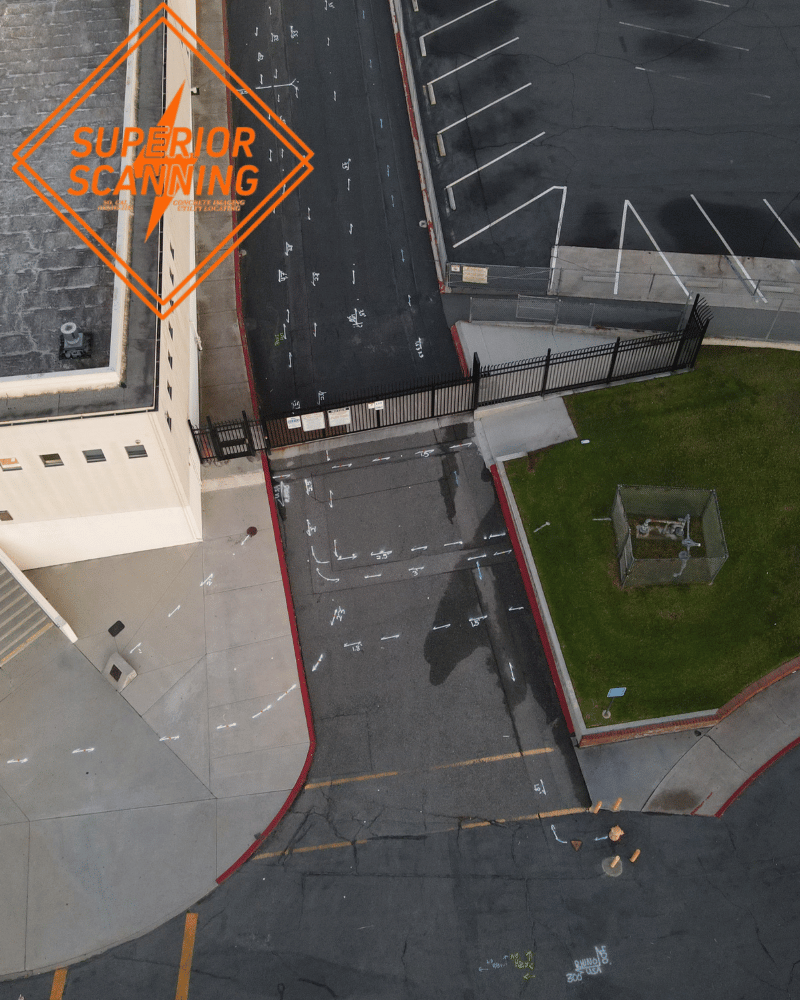 Aerial view of a school parking lot and walkway with painted markings on the asphalt.